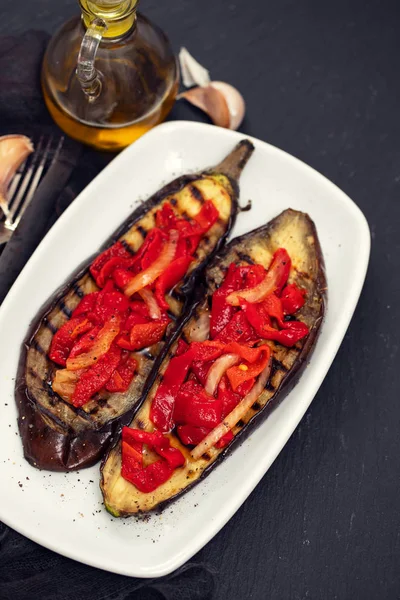 Beyaz çanak üzerinde kırmızı biber ile ızgara patlıcan