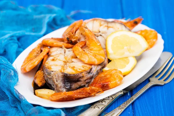 boiled fish with shrimps and lemon on white dish
