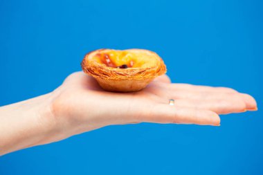 Portekizce yumurta tart mavi arka plan ile kadının elinde