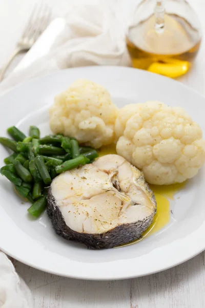 boiled fish with boiled vegetables on white plate