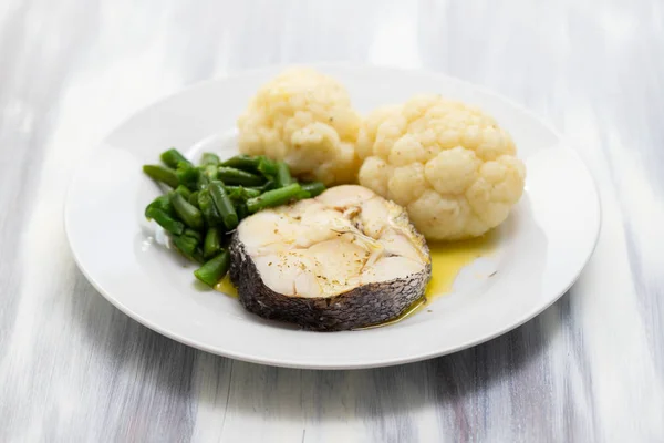 boiled fish with boiled vegetables on white plate