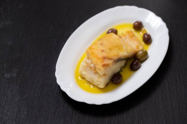 zeytin ve zeytinyağı beyaz çanak üzerinde kızarmış morina balığı