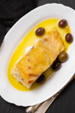 zeytin ve zeytinyağı beyaz çanak üzerinde kızarmış morina balığı