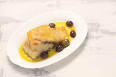 zeytin ve zeytinyağı beyaz çanak üzerinde kızarmış morina balığı