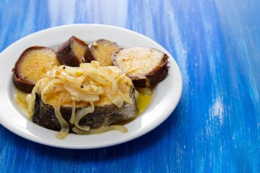 soğan ve tatlı patates üzerinde beyaz tabak haşlanmış balık