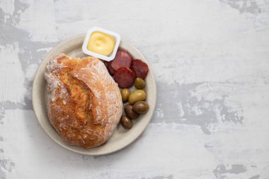 Seramik üzerinde çanak tereyağı, zeytin ve füme sosis ile ekmek 