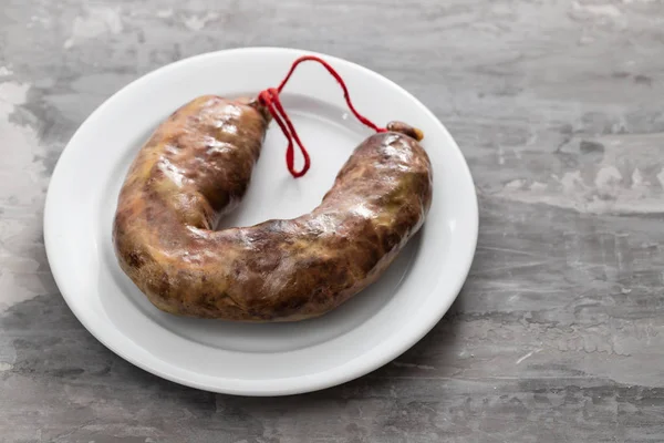 Portuguese smoked sausages on white dish on ceramic background — Stock Photo, Image
