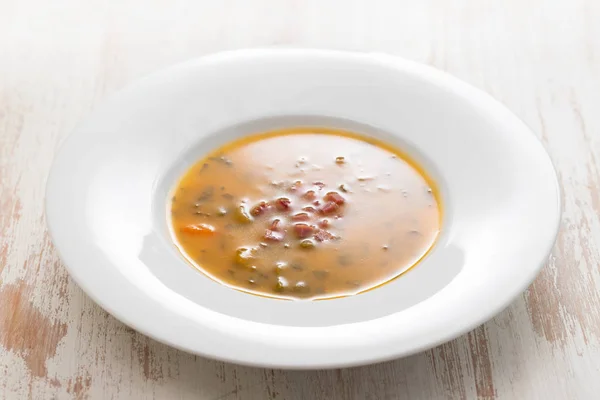 Suppe mit geräuchertem Fleisch in weißem Teller auf hölzerner Schüssel — Stockfoto