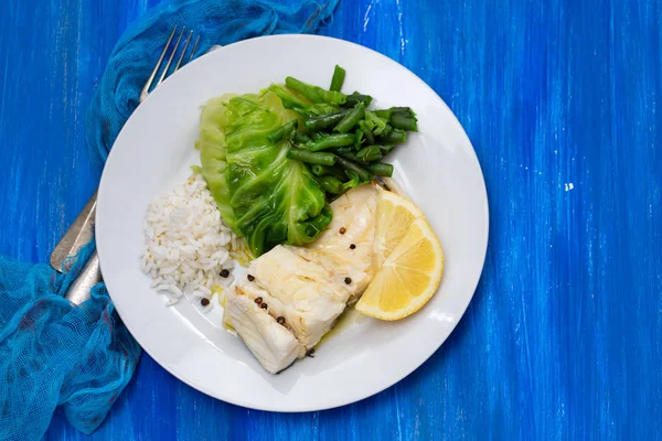 Pescado de bacalao cocido con arroz y verduras en plato blanco — Foto de Stock