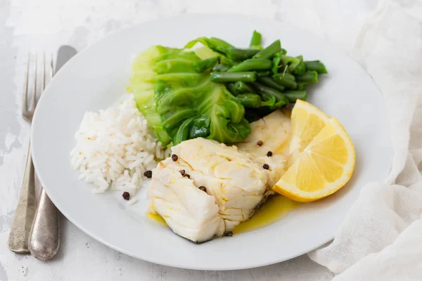 흰 접시에 쌀과 야채를 곁들인 대구 생선 — 스톡 사진