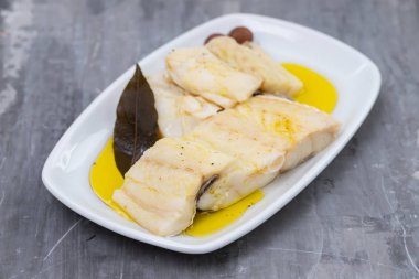 seramik backgrou üzerinde beyaz çanak üzerinde zeytinyağı ile haşlanmış morina balığı