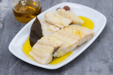 seramik backgrou üzerinde beyaz çanak üzerinde zeytinyağı ile haşlanmış morina balığı