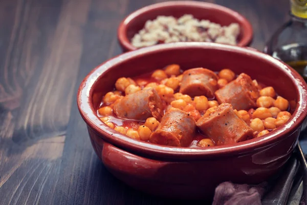 Spanish sausage with chick-pea in small brown ceramic dish — Stock Photo, Image