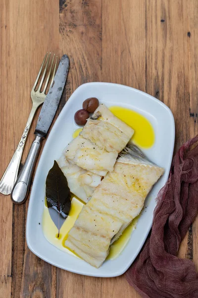 Peixe de bacalhau fervido com folha baia e azeite em prato branco em woo — Fotografia de Stock