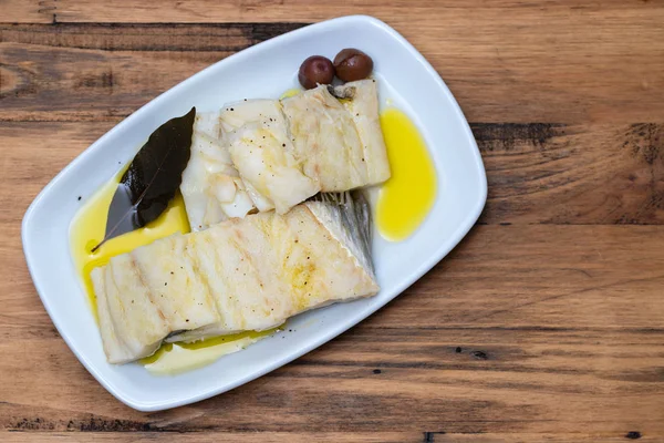 Gekochter Kabeljau mit Lorbeerblatt und Olivenöl auf weißem Teller auf Woo — Stockfoto