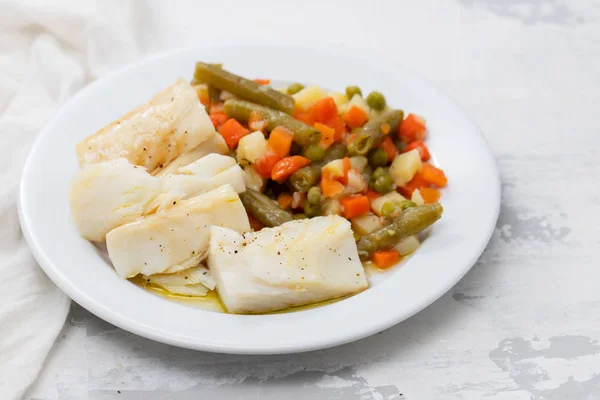 Boiled cod fish with boiled vegetables on white plate on ceramic — Stock Photo, Image