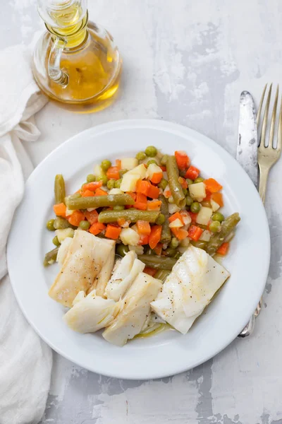 Boiled cod fish with boiled vegetables on white plate on ceramic — Stock Photo, Image