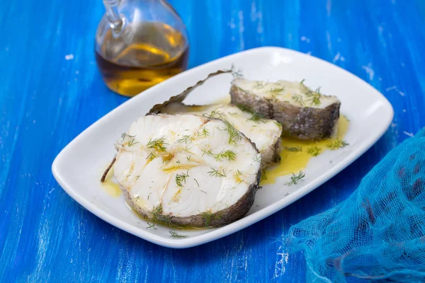 Boiled fish with olive oil in white dish on blue wooden backgrou — Stock Photo, Image