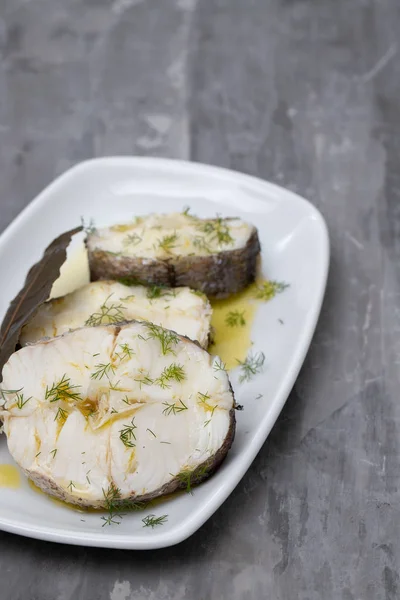 Boiled fish with olive oil  and bay leaf in white dish — Stock Photo, Image