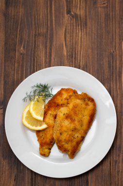 kahverengi ahşap backgrou üzerinde beyaz plaka üzerinde limon ile kızarmış tavuk