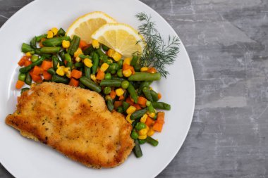 beyaz çanak üzerinde haşlanmış sebze ve limon ile kızarmış tavuk