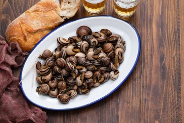 ahşap arka plan üzerinde beyaz çanak otlar ile haşlanmış salyangoz