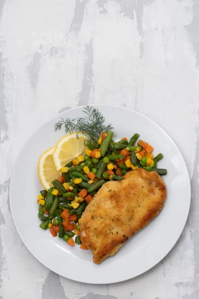 Frango frito com verduras fervidas e limão no prato branco — Fotografia de Stock