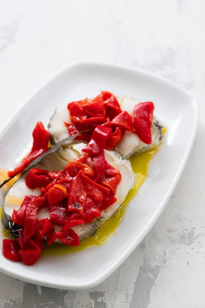 Boiled fish with red pepper and olive oil on white dish — Stock Photo, Image