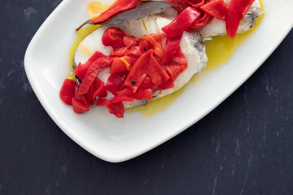 Pescado cocido con pimiento rojo y aceite de oliva sobre plato blanco —  Fotos de Stock