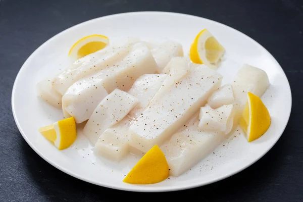 Roher Tintenfisch mit Pfeffer und frischer Zitrone auf weißem Teller — Stockfoto