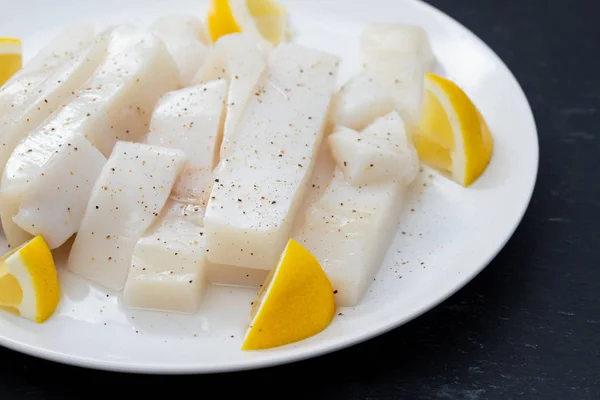 Raw squid with pepper and fresh lemon on white plate — Stock Photo, Image