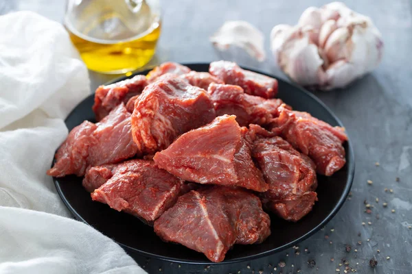 Cerdo crudo en adobo sobre plato negro sobre fondo cerámico — Foto de Stock