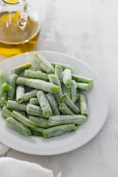 Frijoles verdes congelados sobre plato blanco sobre fondo cerámico —  Fotos de Stock