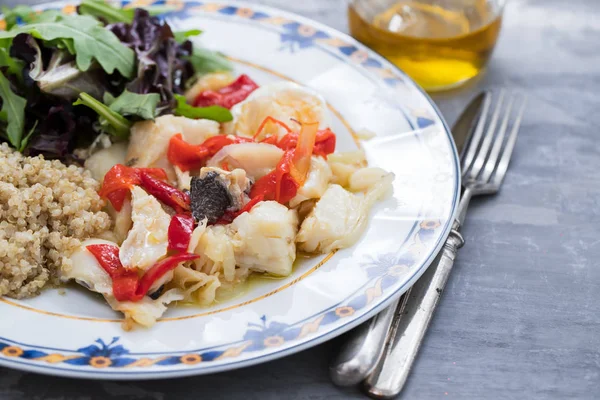Рыба из трески с киноа и свежий салат на блюде и оливковом масле — стоковое фото