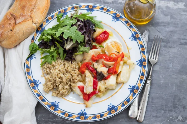 Рыба из трески с киноа и свежий салат на блюде и оливковом масле — стоковое фото