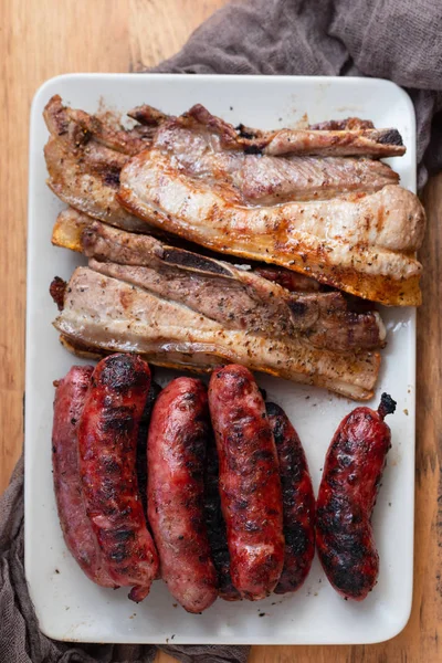 Grillowane mięso i kiełbaski na naczyniu na drewnianym tle — Zdjęcie stockowe