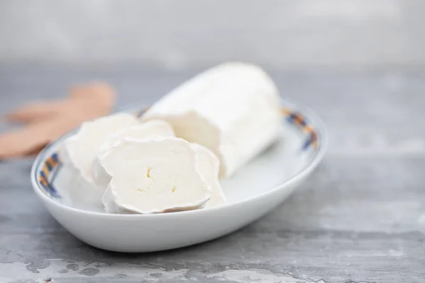 Ziegenkäse auf Teller auf keramischem Hintergrund — Stockfoto