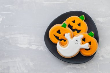 Seramik arkaplanda siyah tabak üzerine Cadılar Bayramı kurabiyeleri