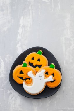 Cadılar Bayramı kurabiyeleri seramik arkaplanda koyu tabakta balkabağı