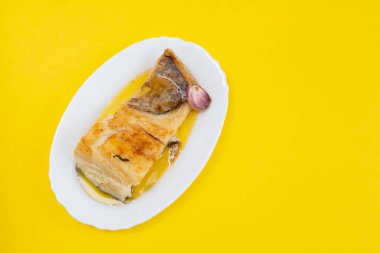 Sarımsaklı kızarmış balık ve beyaz tabakta zeytinyağı.