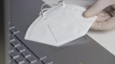 Bilgisayarda eldivenle çalışan, maske takan eller.