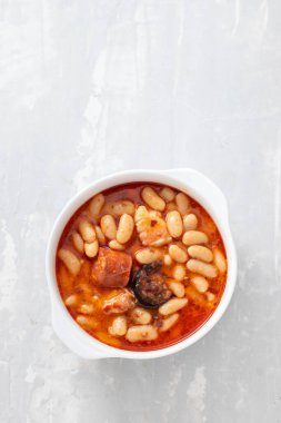Tipik İspanyol yemeği masalı, füme sosisli fasulye ve beyaz tabakta et.