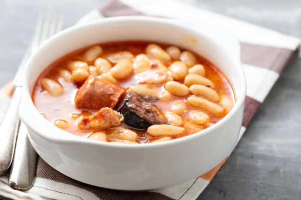 Tipik İspanyol yemeği masalı, füme sosisli fasulye ve beyaz kasede et.