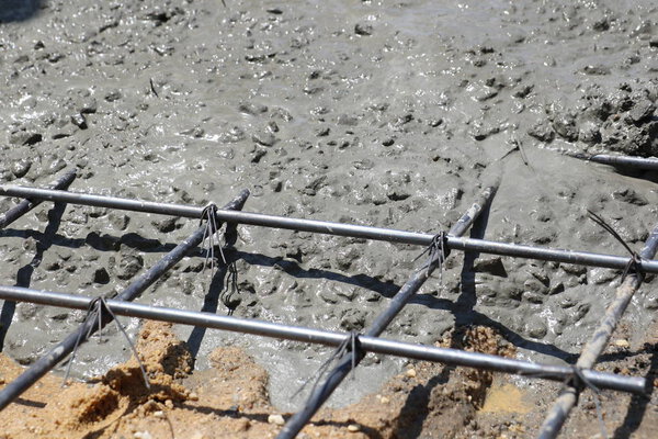 Wet concrete is poured into wire mesh steel rod