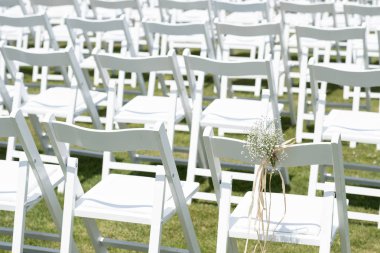 Beyaz çiçeklerle süslü sandalyeler, düğün töreni bölgesi olarak