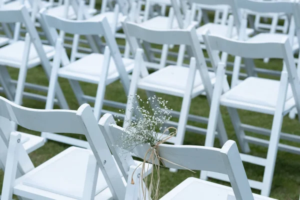 Beyaz çiçeklerle süslü sandalyeler, düğün töreni bölgesi olarak