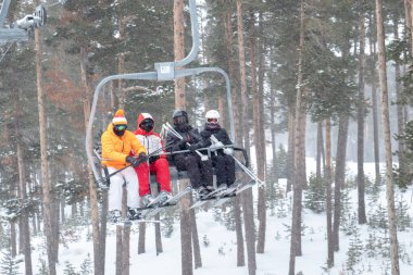 Bir grup neşeli arkadaş dağlarda kayak yapmak için teleferiğe biniyorlar.