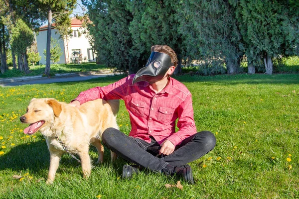 boy wearing old style virus mask   with his dog playing at garden