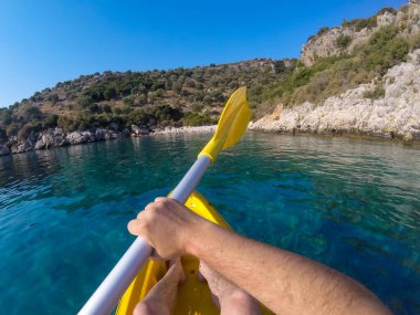 Yaz tatilinde mavi deniz suyunda renkli sarı bir kano.
