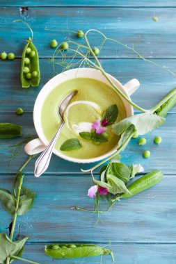 Mavi ahşap zemin üzerine krem yeşil bezelye çorbası